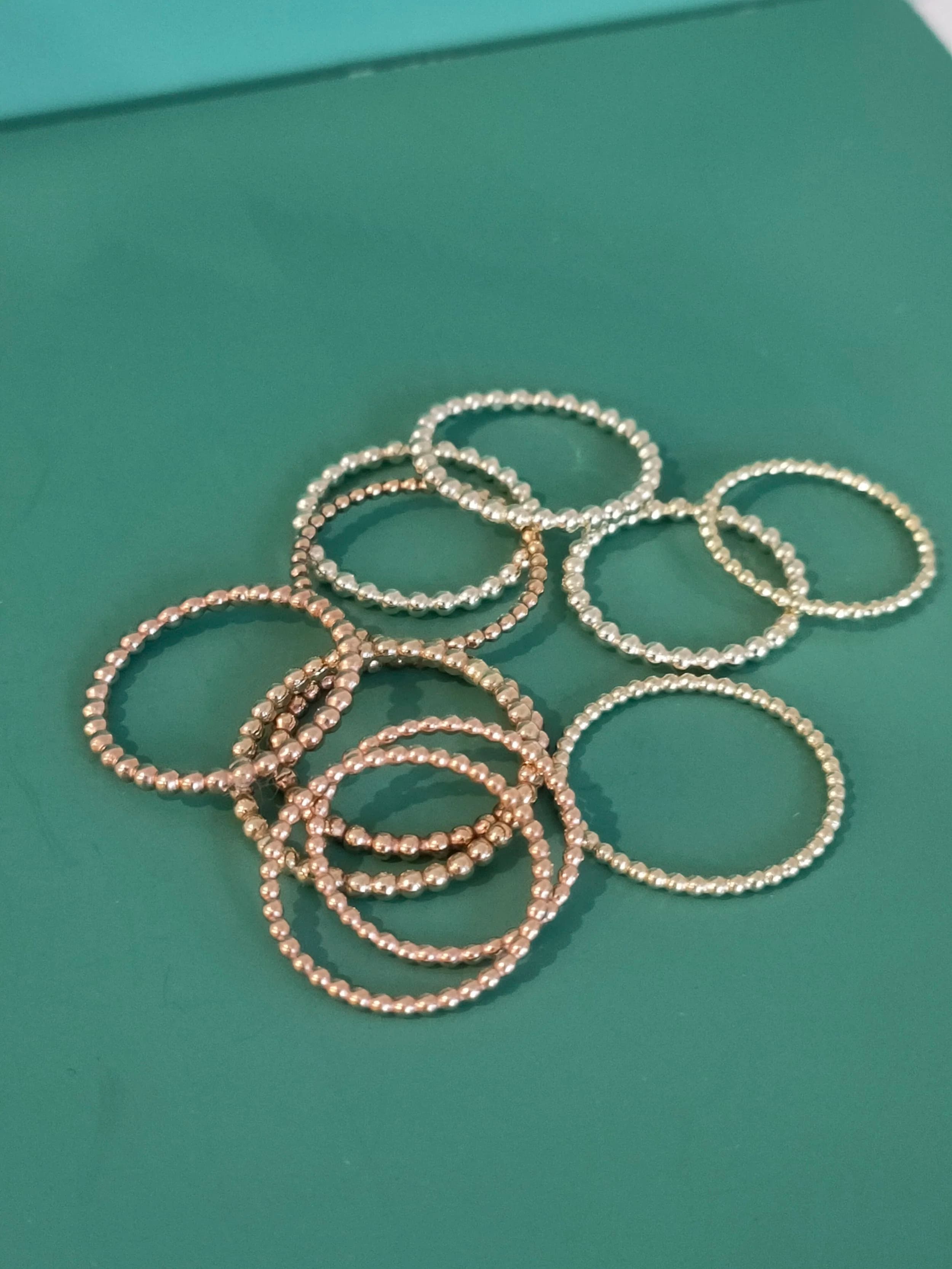 Original phone photo of gold beaded rings on a green workbench mat